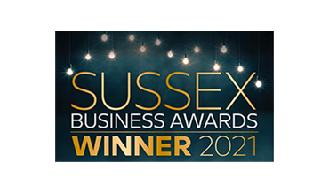"Sussex Business Awards Winner 2021" in gold and white writing with a blue background with stage lights framing the top of the image and some text