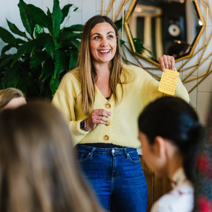 2 women talking to a small group of people, looking happy whilst doing it