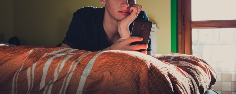 Teenager using phone in bedroom header with overlay