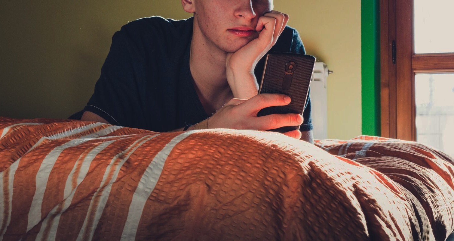 Teenager using phone in bedroom header with overlay