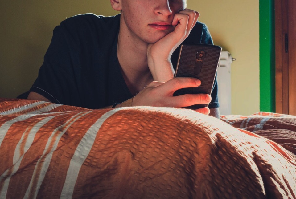 Teenager using phone in bedroom header with overlay