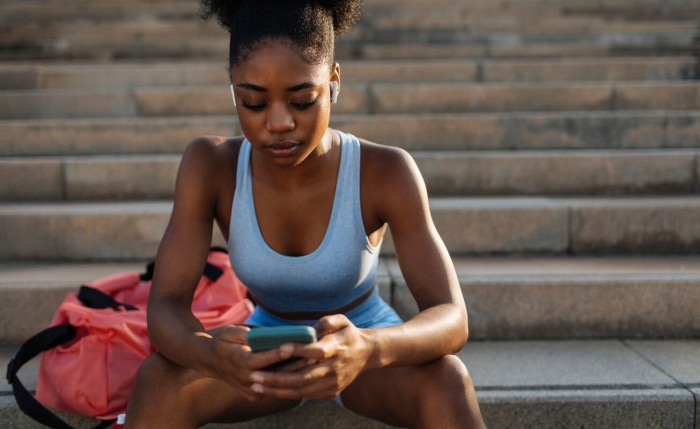 Woman uses phone before working out Website image gallery