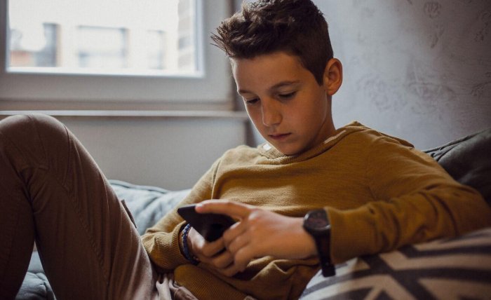Teenager using their phone in their bedroom Website image gallery