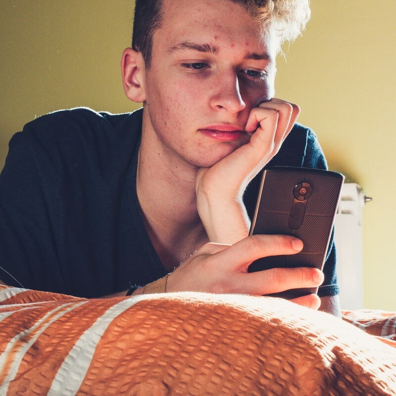 Teenager using phone in bedroom Client story header